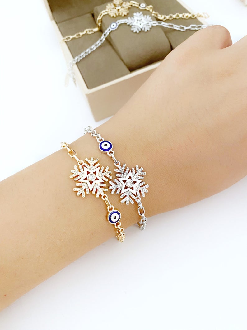 Elegant Evil Eye Chain Bracelet featuring a blue evil eye, snowflake charm, and clover charm, available in gold and silver finishes.