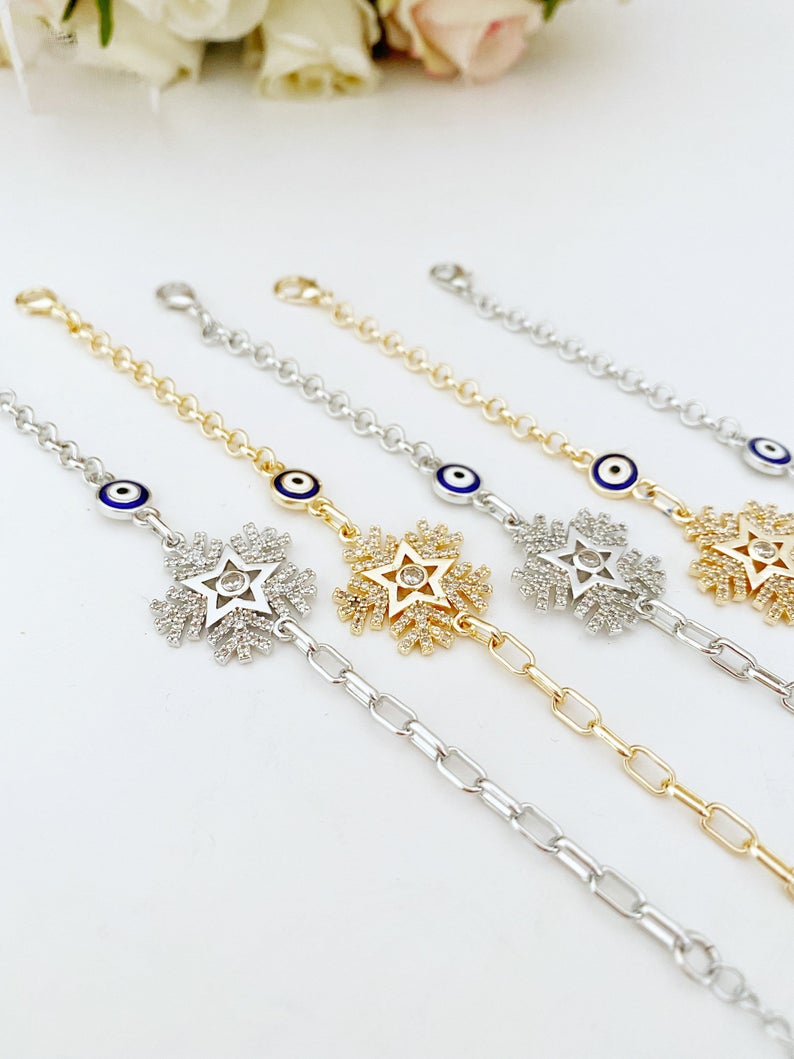 Elegant Evil Eye Chain Bracelet featuring a blue evil eye, snowflake charm, and clover charm, available in gold and silver finishes.