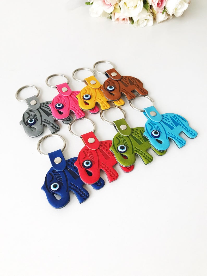 A beautifully crafted Elephant evil eye keychain featuring suede leather, resin evil eye beads, and a silver keychain hook, available in various colors.