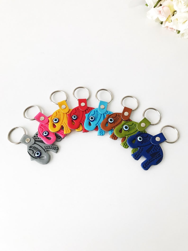 A beautifully crafted Elephant evil eye keychain featuring suede leather, resin evil eye beads, and a silver keychain hook, available in various colors.