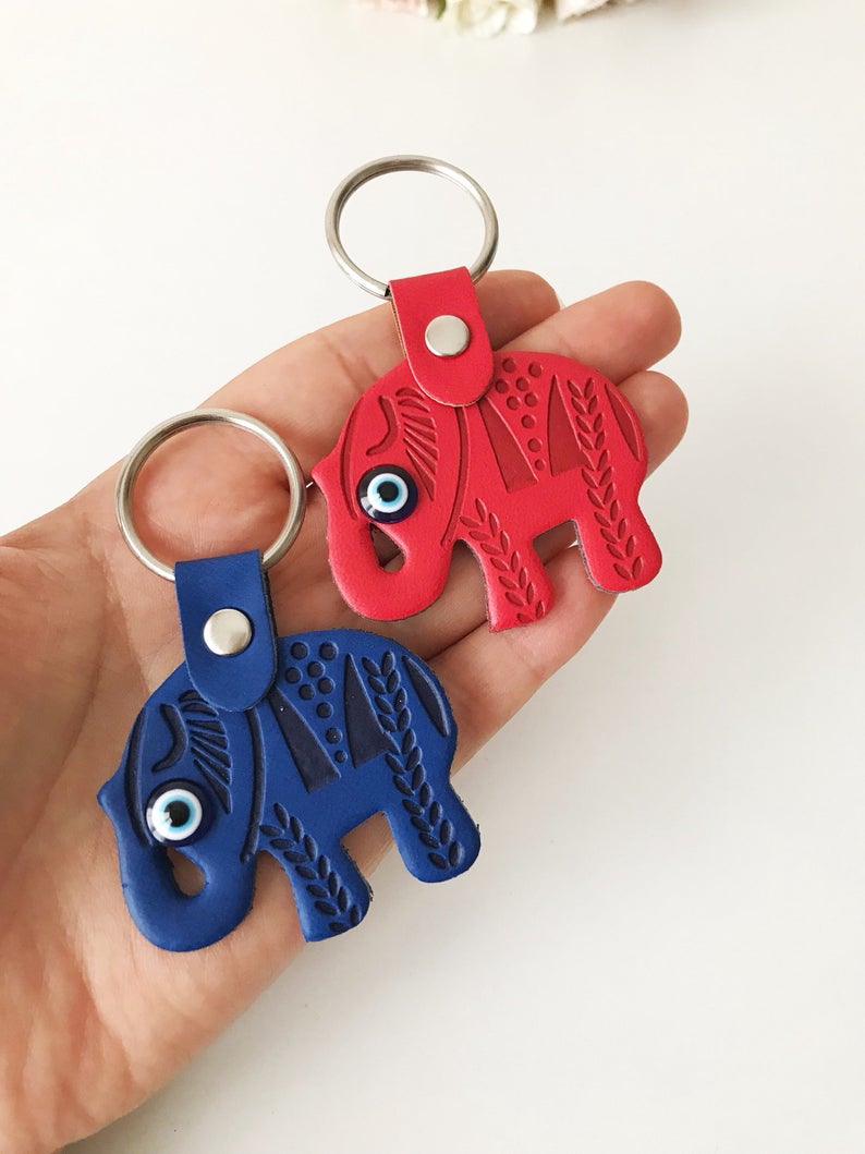 A beautifully crafted Elephant evil eye keychain featuring suede leather, resin evil eye beads, and a silver keychain hook, available in various colors.