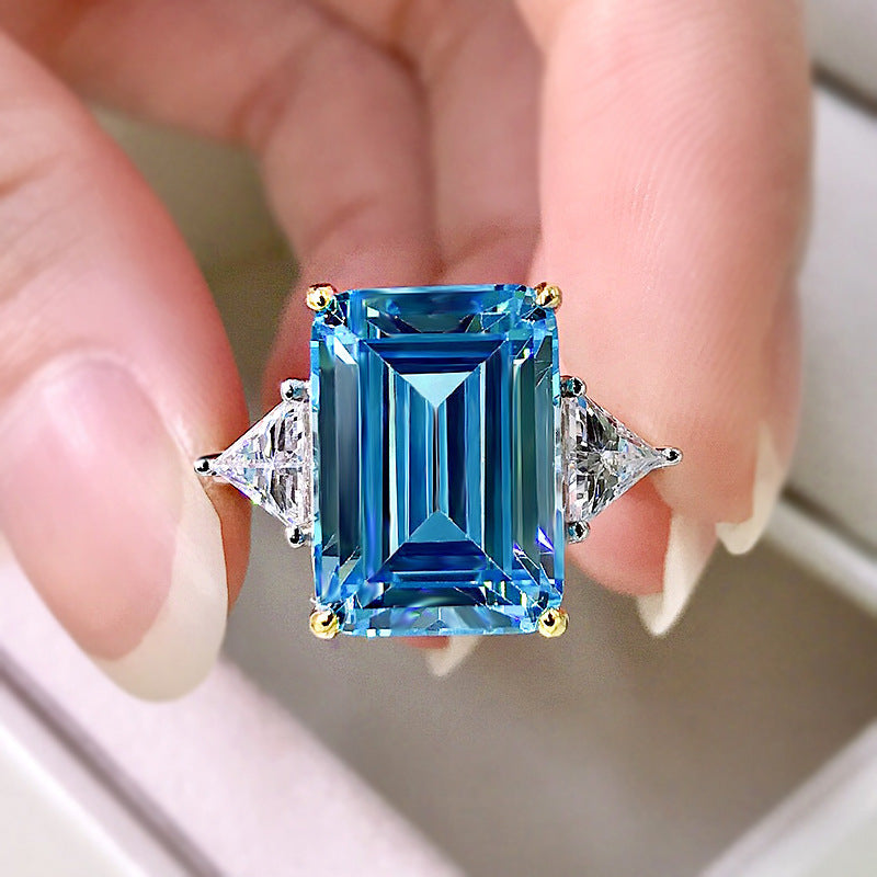 Elegant emerald cut aquamarine ring set in 925 sterling silver with white sapphire accents, showcasing a sparkling blue gemstone.