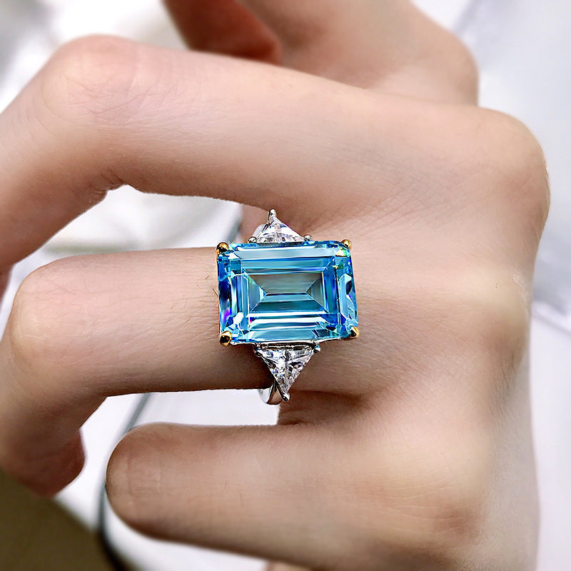 Elegant emerald cut aquamarine ring set in 925 sterling silver with white sapphire accents, showcasing a sparkling blue gemstone.