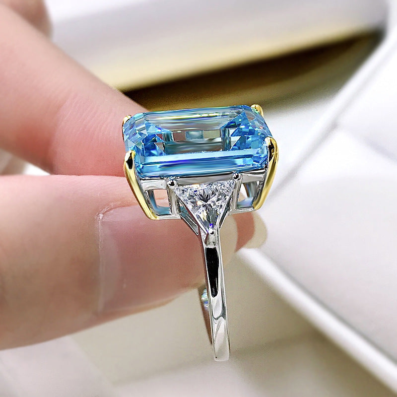 Elegant emerald cut aquamarine ring set in 925 sterling silver with white sapphire accents, showcasing a sparkling blue gemstone.