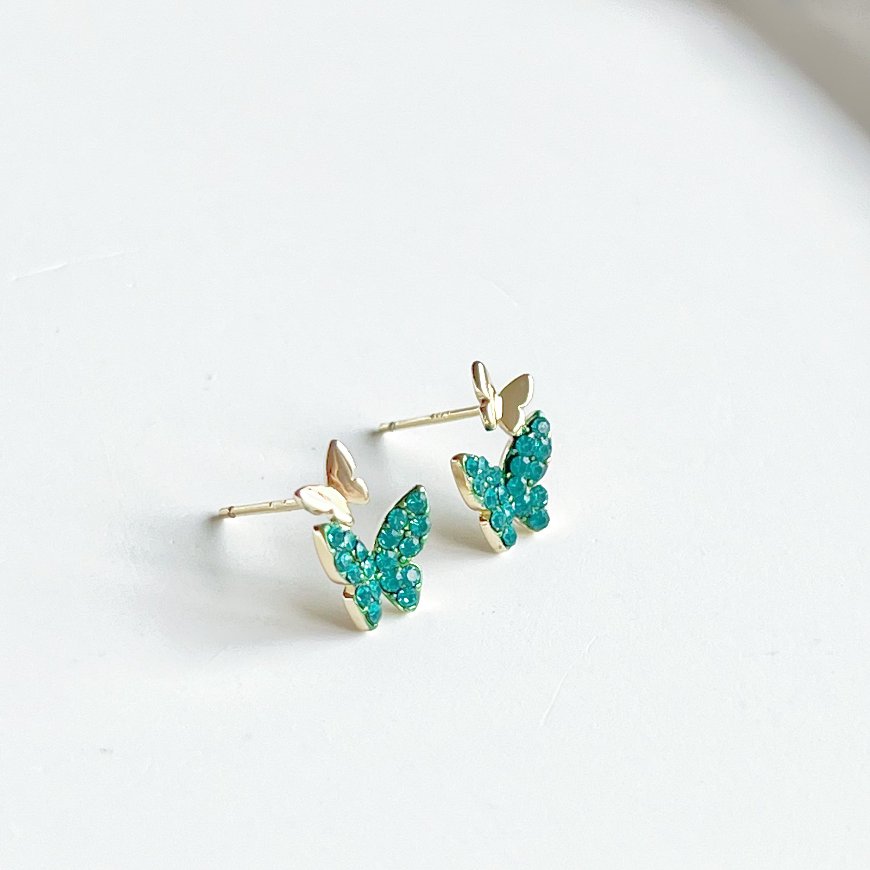 Emerald green crystal butterflies earrings made of gold-plated sterling silver and bronze, featuring sparkling green zircon stones.