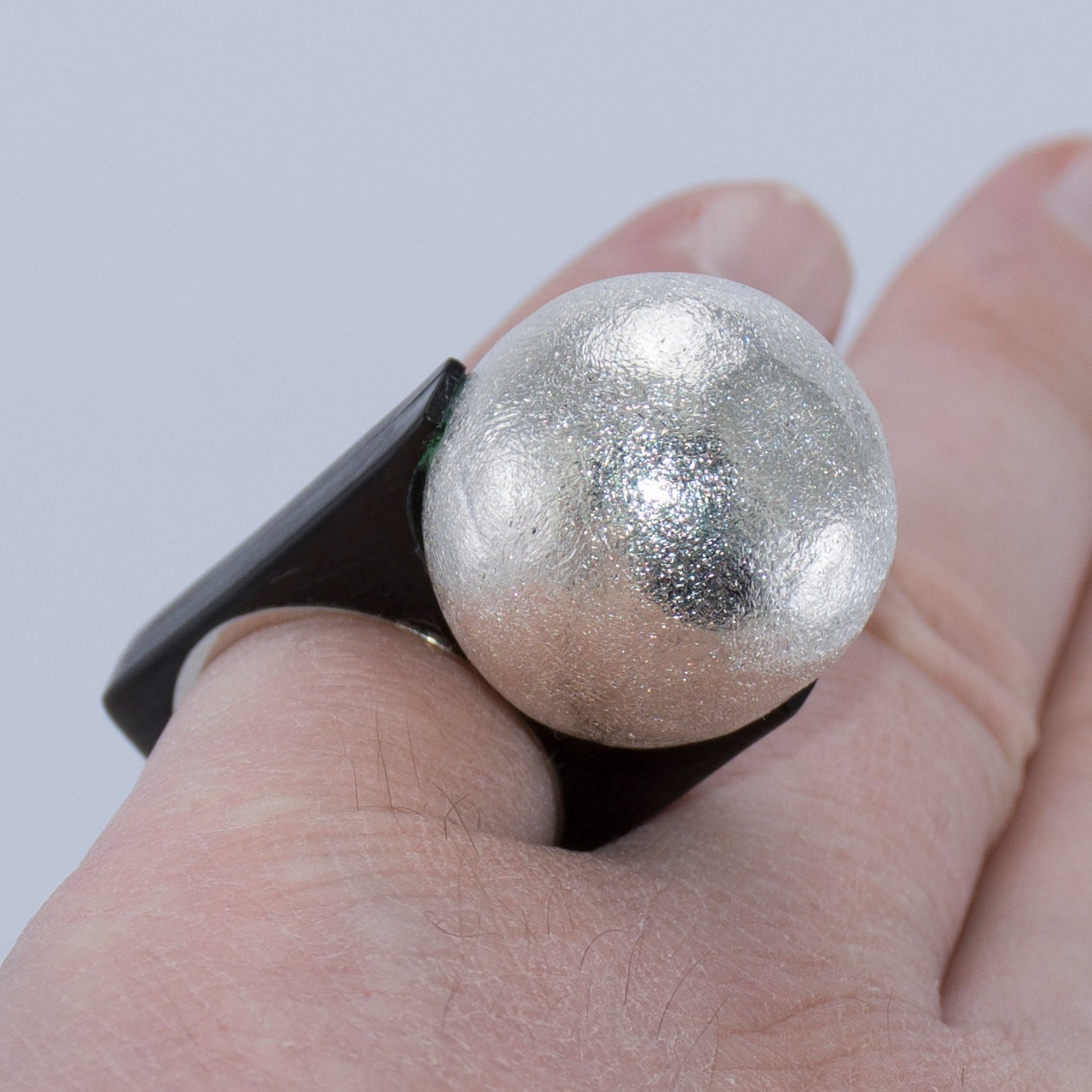 A unique engagement ring made from buffalo horn with a silver ball accent, showcasing its handcrafted design.