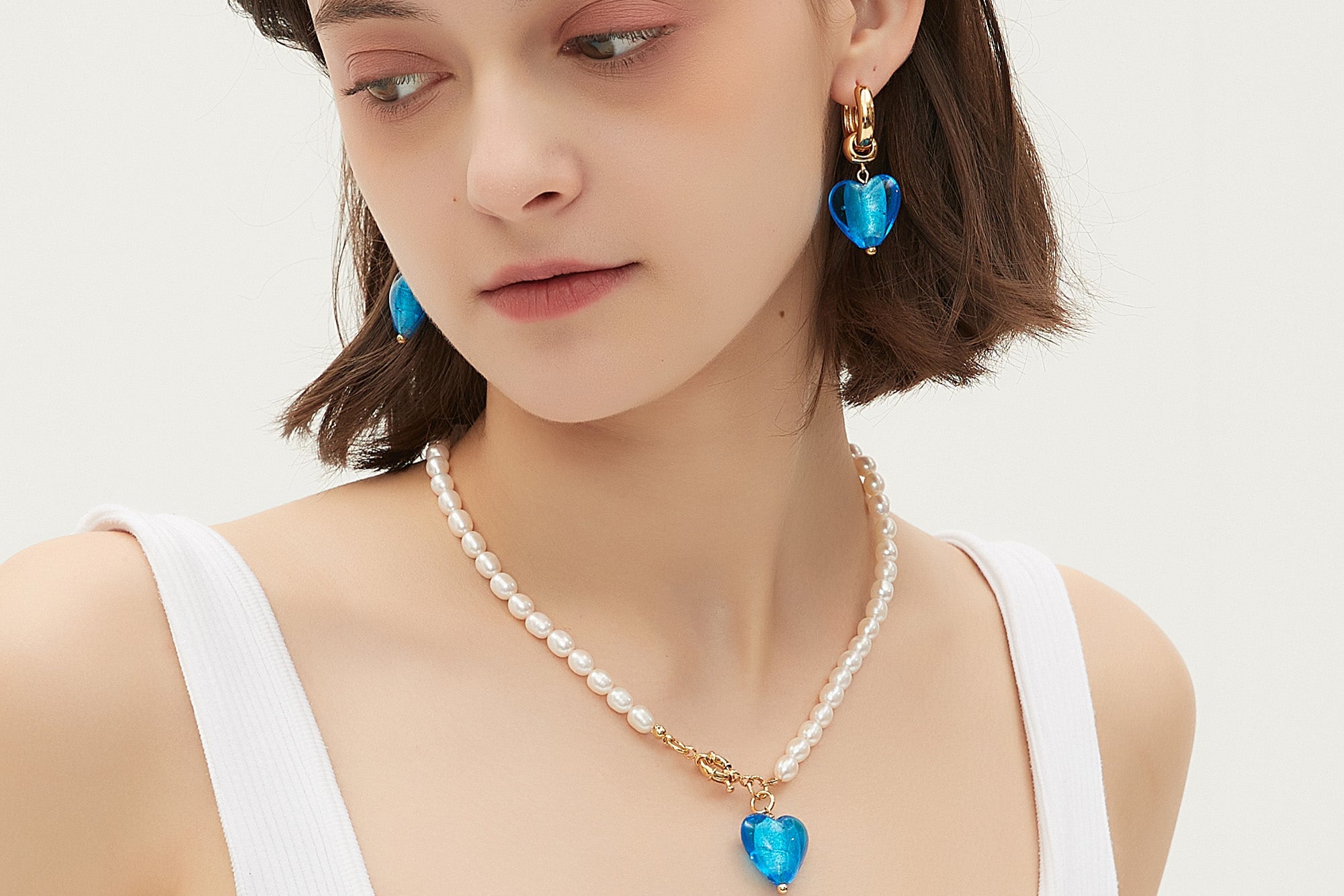 Esmée Sky Blue Glaze Heart Dangle Earrings featuring colorful handmade glass hearts and 18k gold plated hoops.