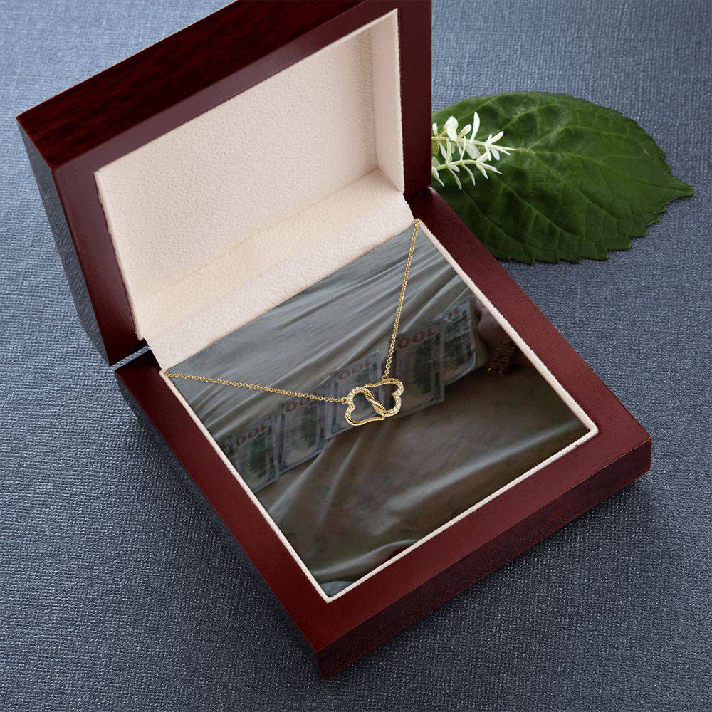 A beautiful Everlasting Love necklace featuring two connected 10K gold hearts adorned with 18 sparkling diamonds, presented in a luxurious mahogany gift box.