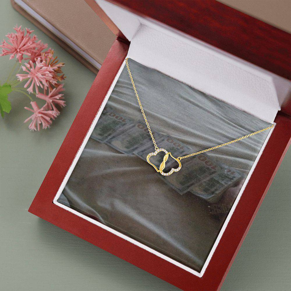 A beautiful Everlasting Love necklace featuring two connected 10K gold hearts adorned with 18 sparkling diamonds, presented in a luxurious mahogany gift box.