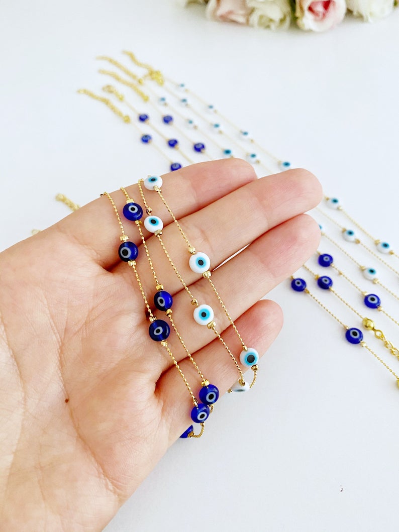 A delicate gold chain anklet featuring tiny blue and white evil eye beads, perfect for minimalist jewelry lovers.