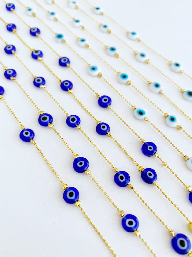 A delicate gold chain anklet featuring tiny blue and white evil eye beads, perfect for minimalist jewelry lovers.