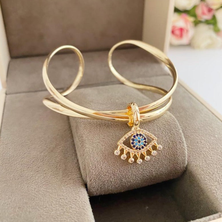 Adjustable Evil Eye Bangle Bracelet in gold with a movable oval charm, showcasing intricate handmade design.