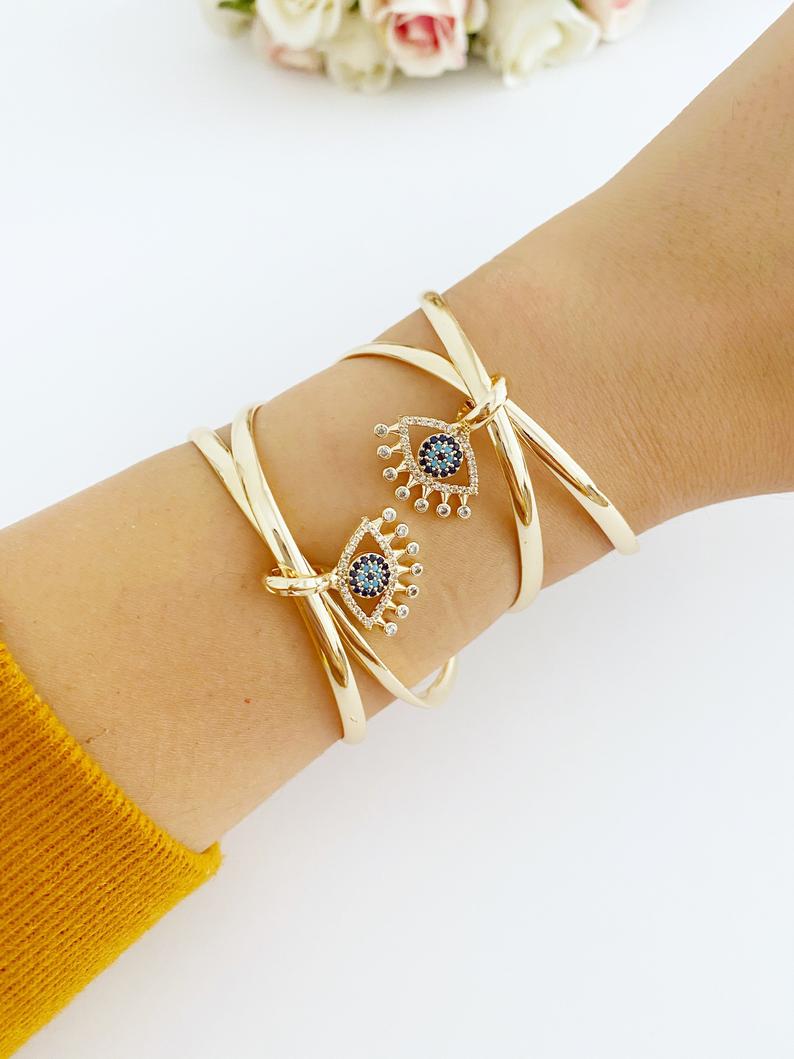 Adjustable Evil Eye Bangle Bracelet in gold with a movable oval charm, showcasing intricate handmade design.