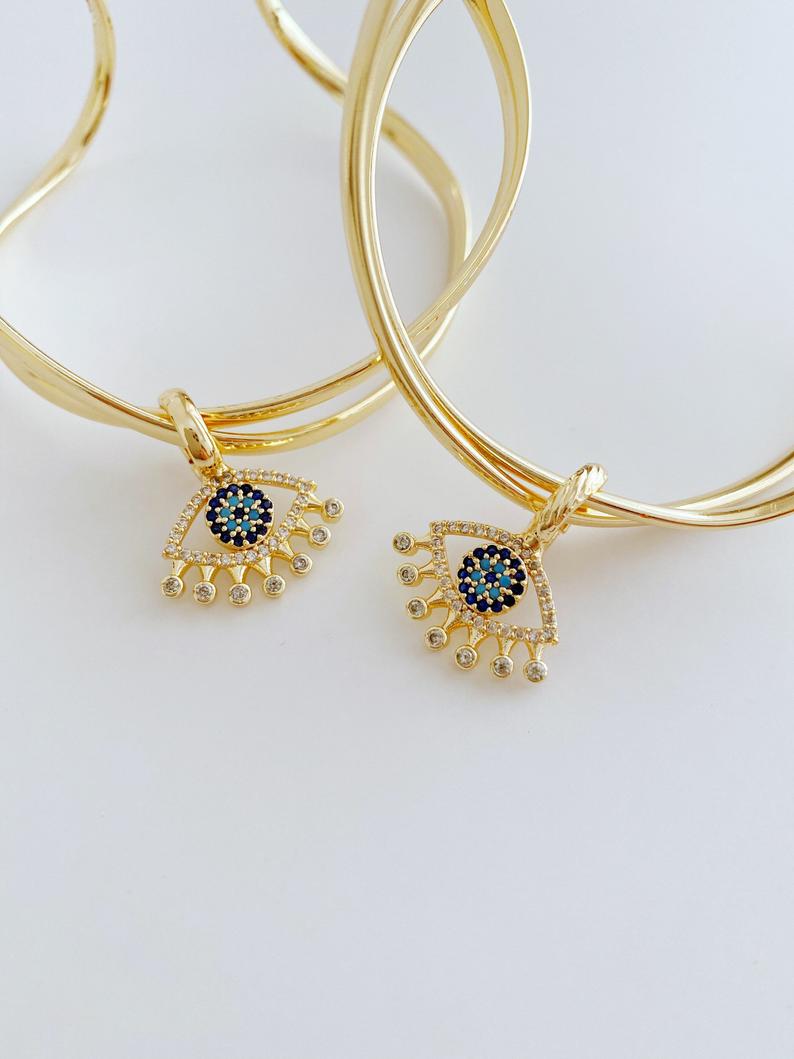 Adjustable Evil Eye Bangle Bracelet in gold with a movable oval charm, showcasing intricate handmade design.