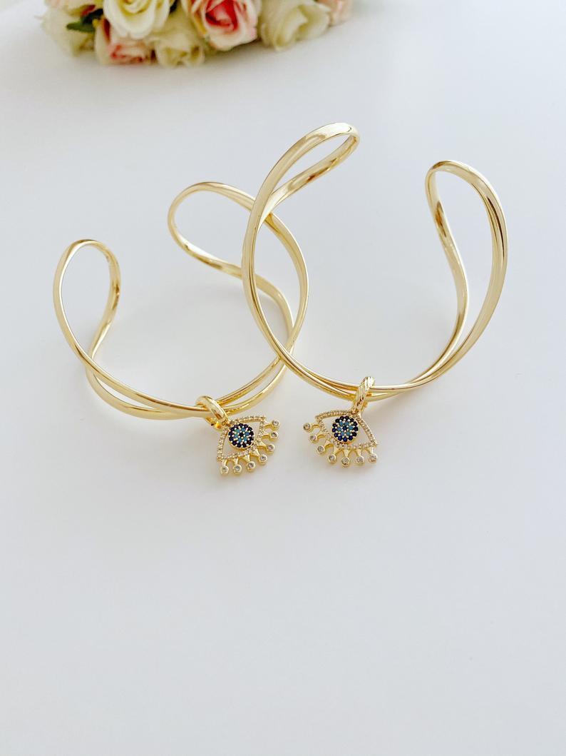 Adjustable Evil Eye Bangle Bracelet in gold with a movable oval charm, showcasing intricate handmade design.