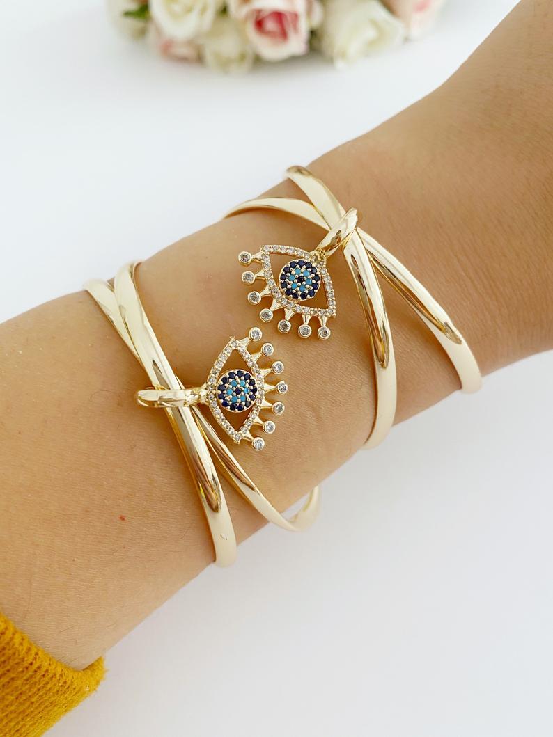 Adjustable Evil Eye Bangle Bracelet in gold with a movable oval charm, showcasing intricate handmade design.