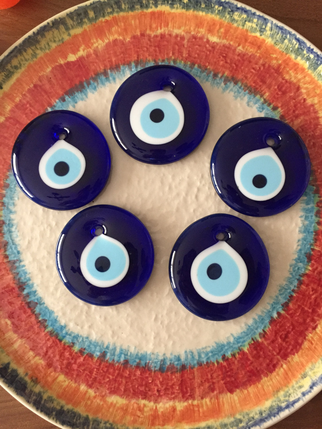 A set of five 7cm handmade evil eye beads, featuring vibrant blue colors and intricate designs, perfect for wall hanging or car décor.