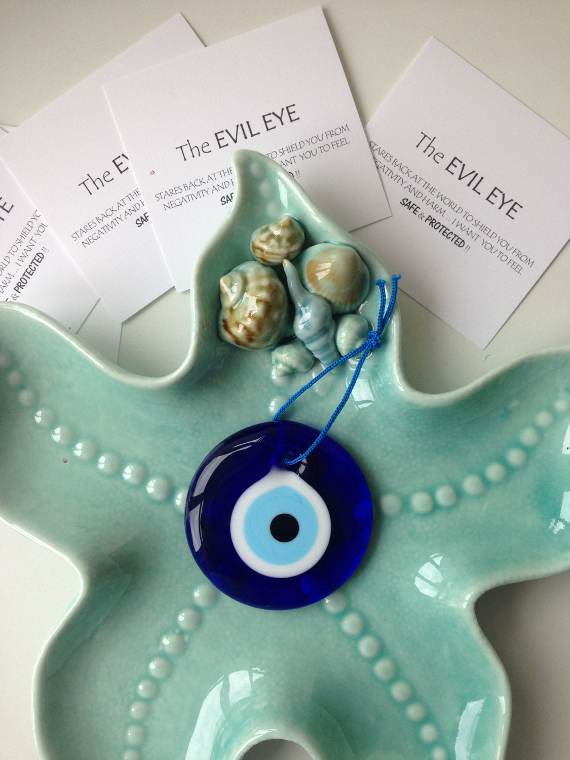 A handmade 7cm evil eye wall hanging featuring a vibrant blue bead and rope, symbolizing protection and good luck.