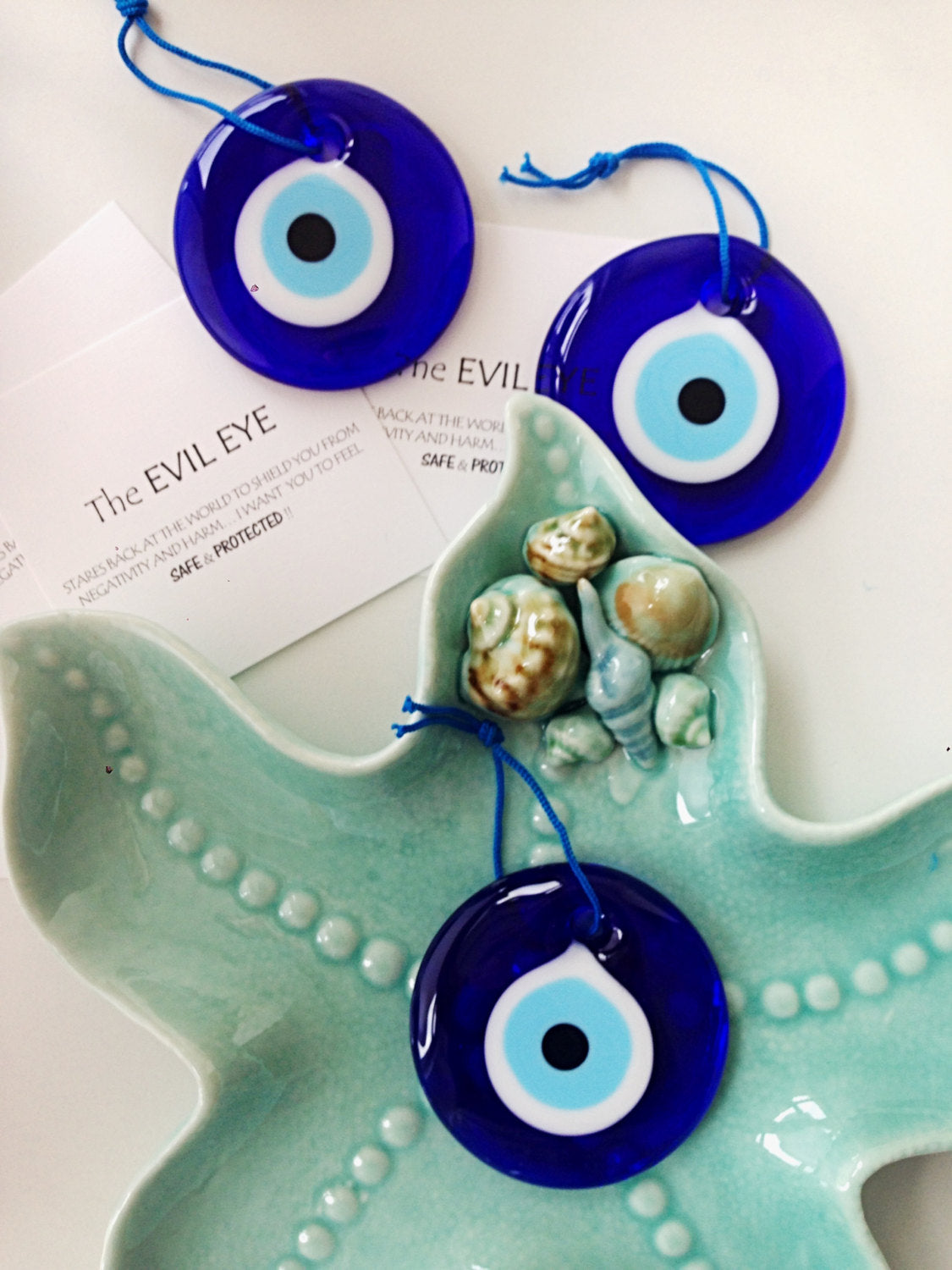 A handmade 7cm evil eye wall hanging featuring a vibrant blue bead and rope, symbolizing protection and good luck.