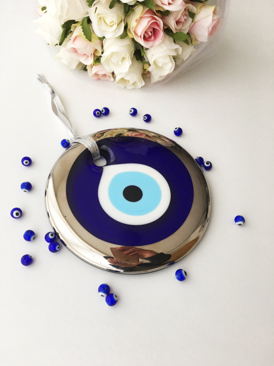 A beautifully handcrafted 13cm Evil Eye Bead with silver trim, featuring a vibrant blue color and a blue rope for hanging.