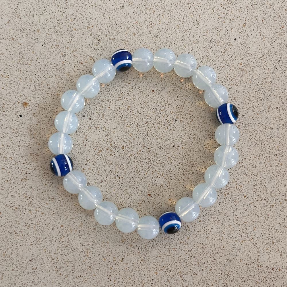 Evil Eye Beaded Stretch Bracelet featuring opalite beads, symbolizing protection and good luck, elegantly displayed on a soft surface.