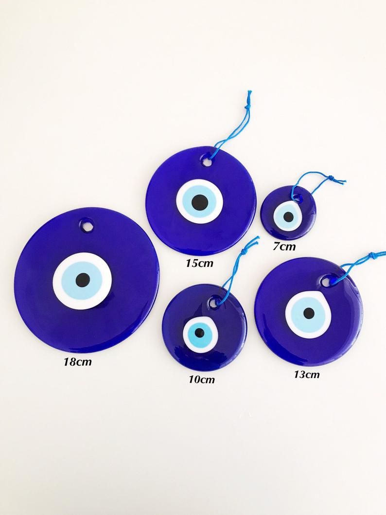 A collection of blue glass evil eye beads in various sizes, showcasing their round shape and vibrant color, perfect for wall hangings and tree decor.