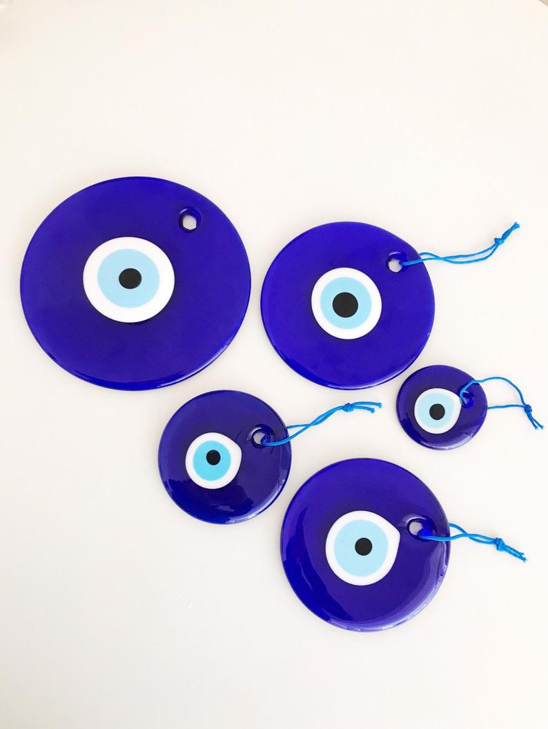 A collection of blue glass evil eye beads in various sizes, showcasing their round shape and vibrant color, perfect for wall hangings and tree decor.