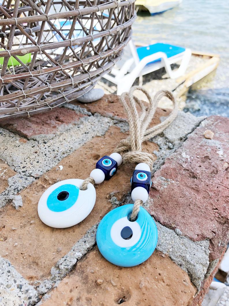 Handmade macrame wall hanging featuring white and blue evil eye beads, symbolizing protection and good luck.