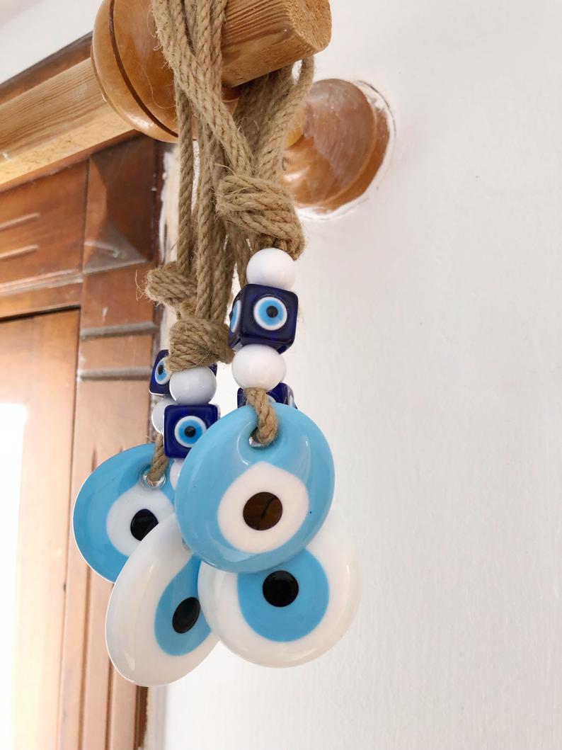 Handmade macrame wall hanging featuring white and blue evil eye beads, symbolizing protection and good luck.