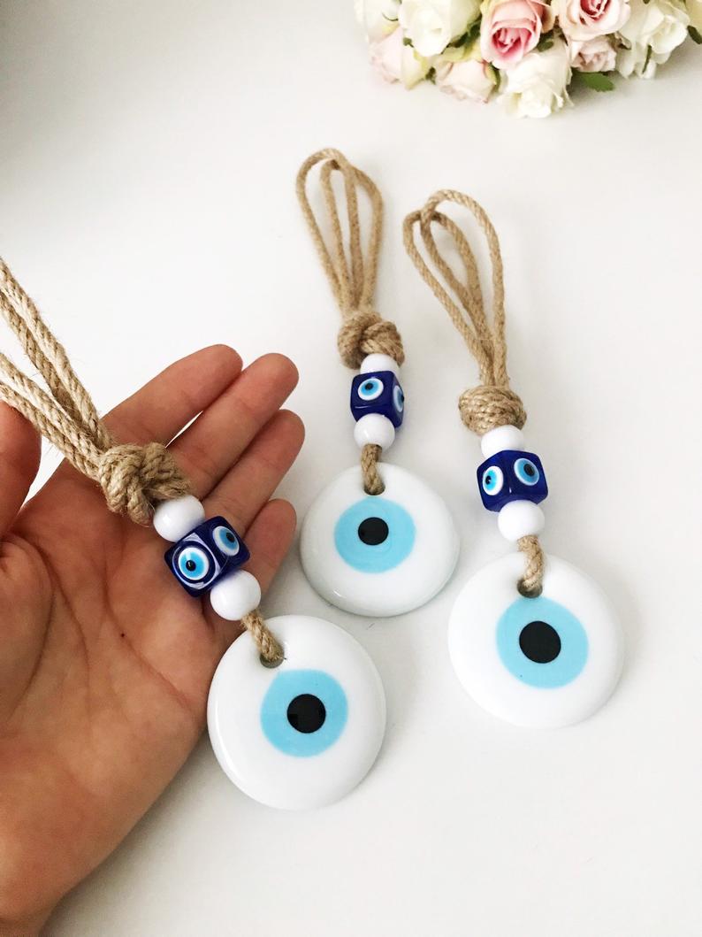 Handmade macrame wall hanging featuring white and blue evil eye beads, symbolizing protection and good luck.