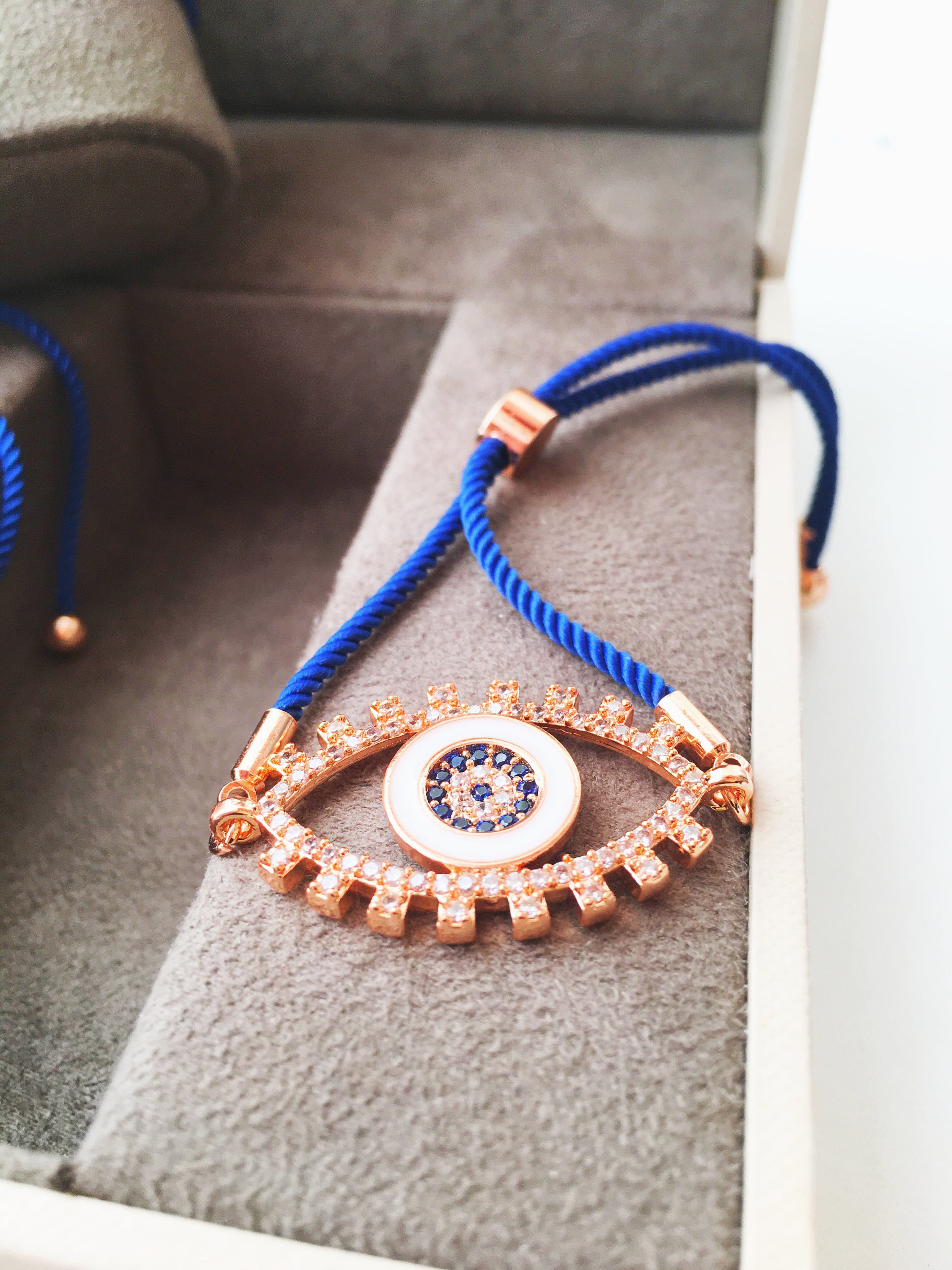 Handmade Evil Eye Bracelet with blue string and zirconia charm, featuring adjustable design and rose gold accents.