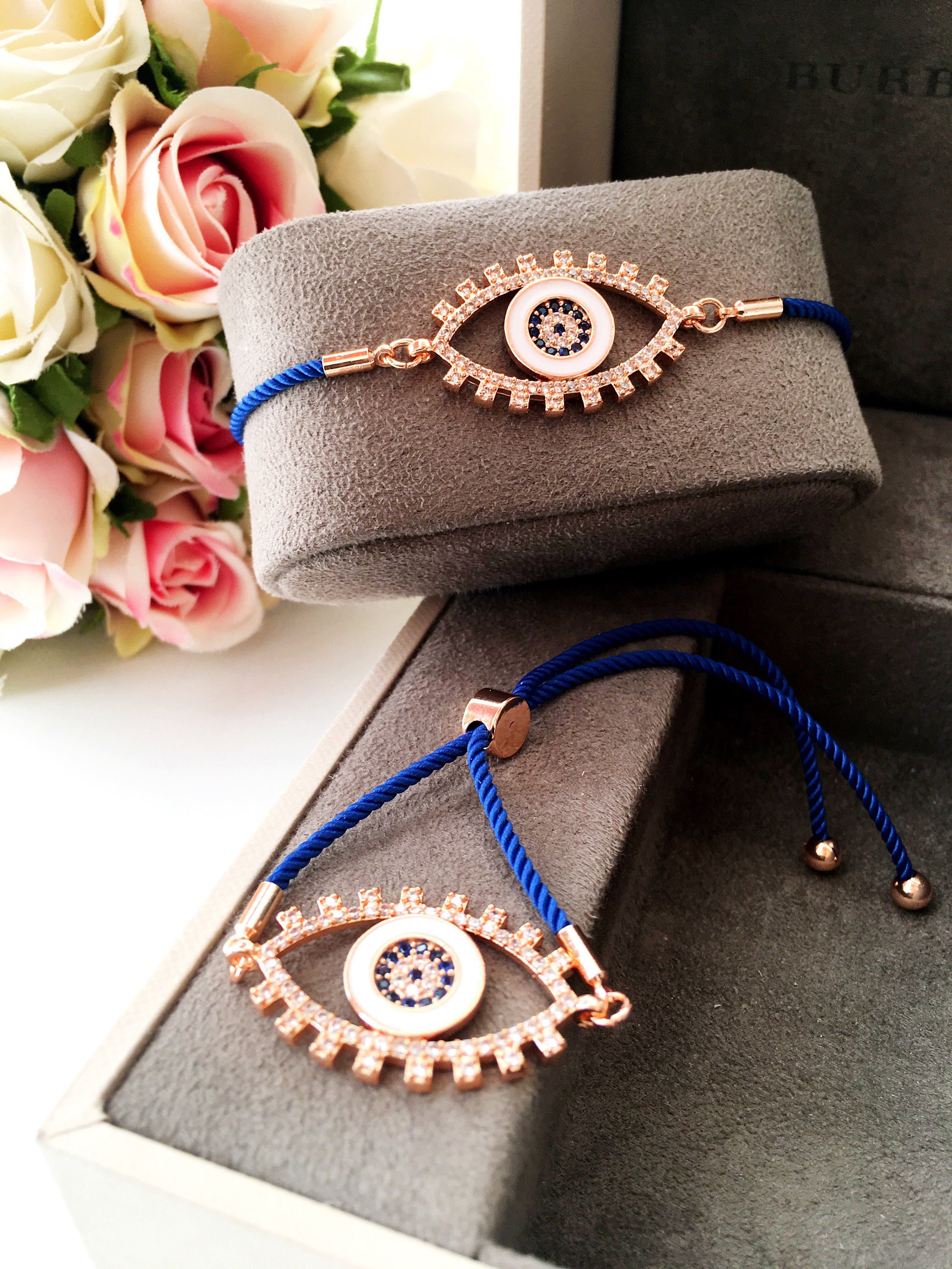 Handmade Evil Eye Bracelet with blue string and zirconia charm, featuring adjustable design and rose gold accents.