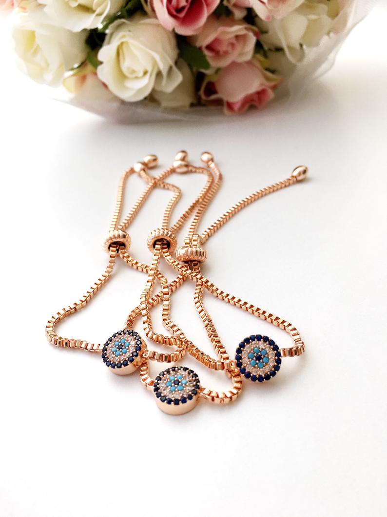 A beautiful rose gold Evil Eye Bracelet set featuring various designs including a tiny evil eye bead, bangle, adjustable cat, and tree of life bracelet.