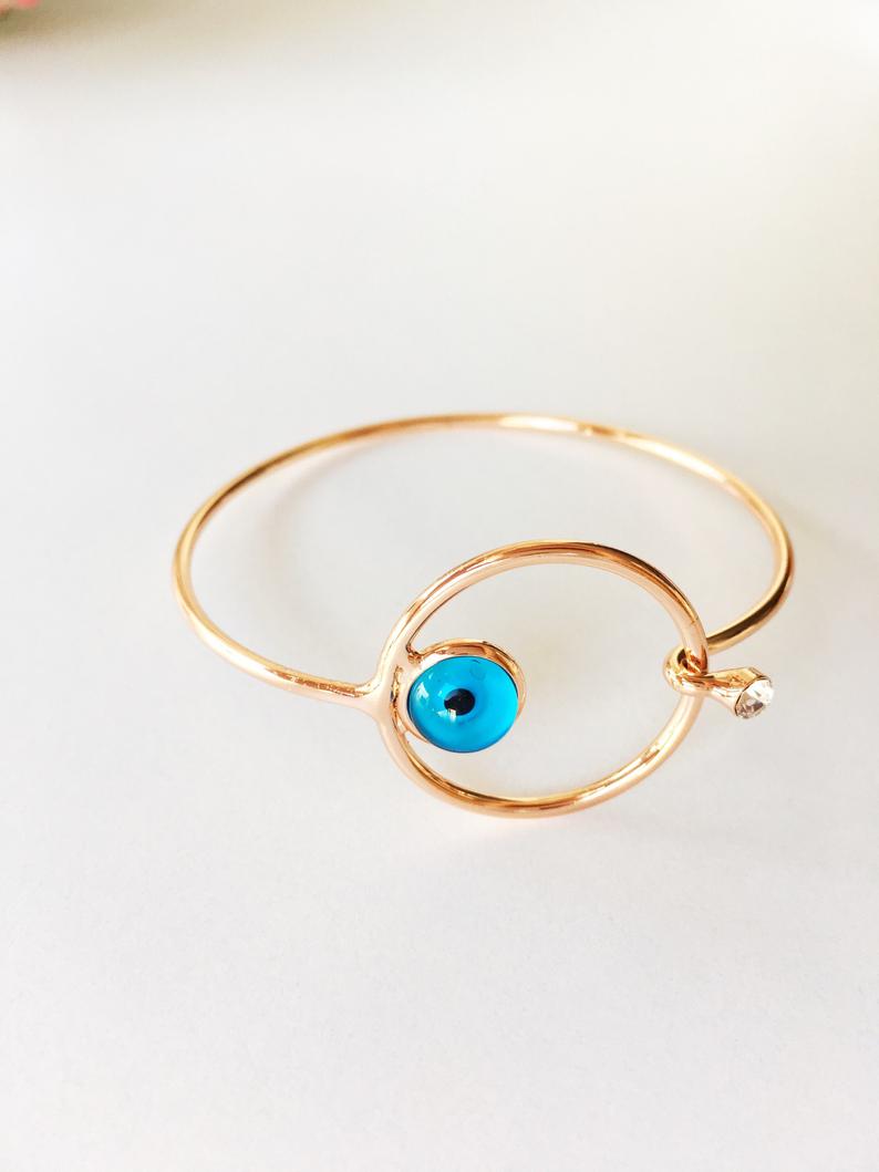 A beautiful rose gold Evil Eye Bracelet set featuring various designs including a tiny evil eye bead, bangle, adjustable cat, and tree of life bracelet.