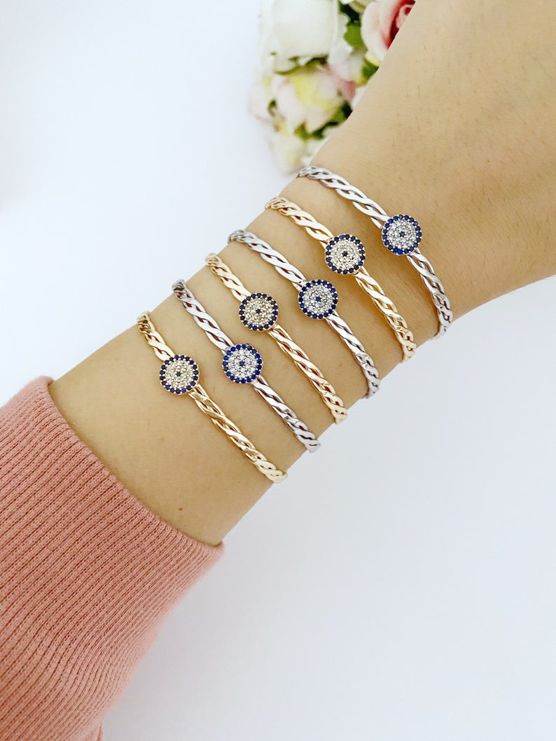 A beautiful evil eye bracelet featuring a movable charm, adjustable design, and available in silver and gold finishes, made from durable stainless steel.