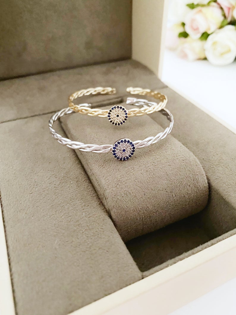 A beautiful evil eye bracelet featuring a movable charm, adjustable design, and available in silver and gold finishes, made from durable stainless steel.