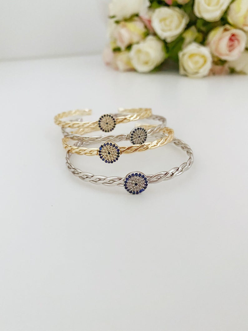 A beautiful evil eye bracelet featuring a movable charm, adjustable design, and available in silver and gold finishes, made from durable stainless steel.