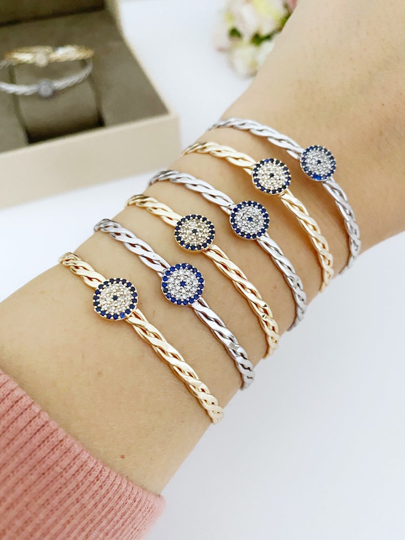 A beautiful evil eye bracelet featuring a movable charm, adjustable design, and available in silver and gold finishes, made from durable stainless steel.