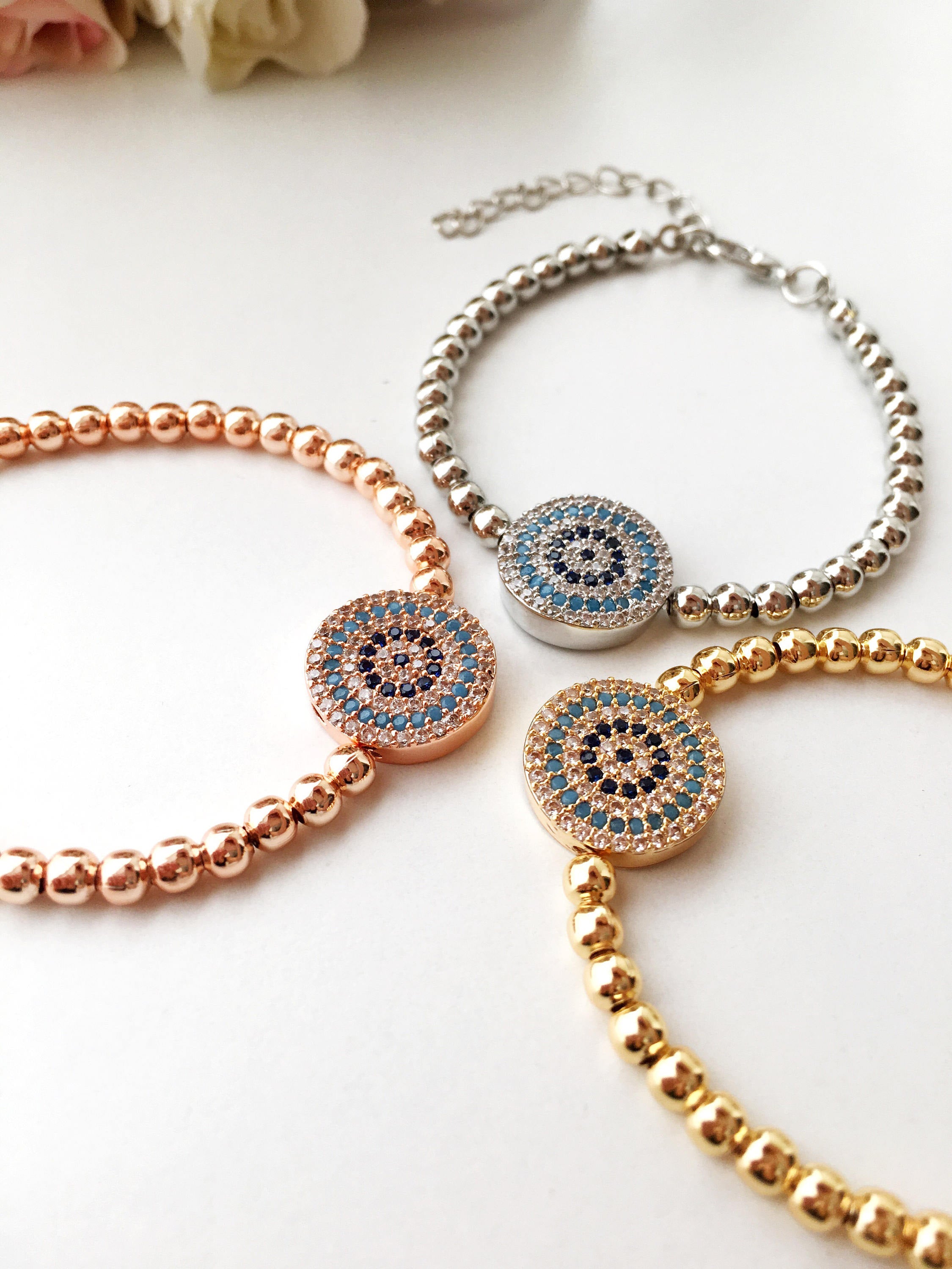 A beautiful Evil Eye Bracelet featuring adjustable beaded chain design in silver, gold, and rose gold finishes, adorned with zirconia accents.