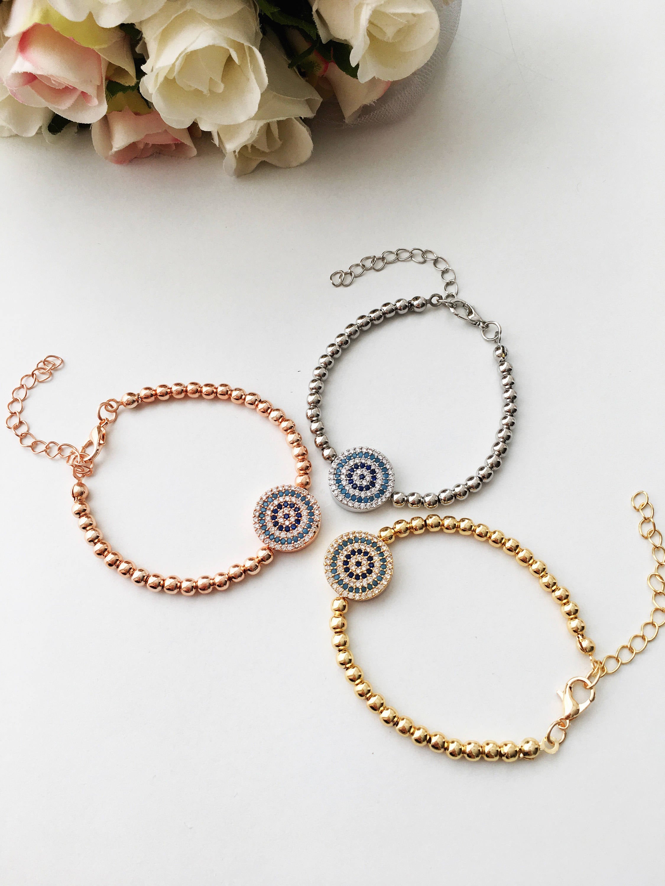 A beautiful Evil Eye Bracelet featuring adjustable beaded chain design in silver, gold, and rose gold finishes, adorned with zirconia accents.