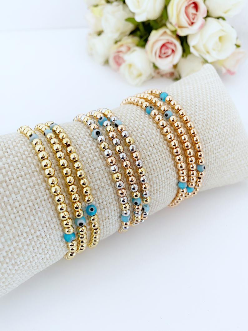 Elegant Evil Eye Bracelet featuring gold balls and a protective charm, available in gold, rose gold, and mixed colors.