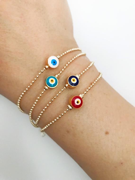 A beautiful gold evil eye bracelet featuring a blue evil eye bead, adjustable stainless steel chain, and available in four colors.