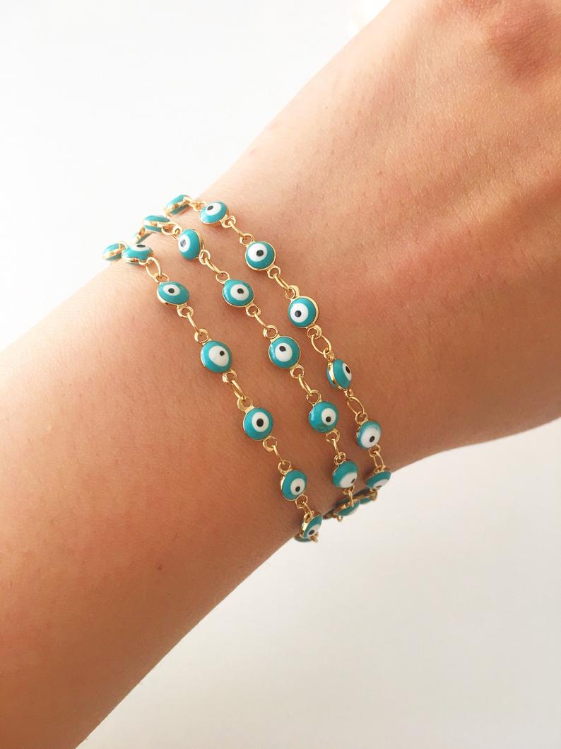 A minimalist evil eye bracelet featuring a gold link chain and turquoise glass beads, symbolizing protection and style.