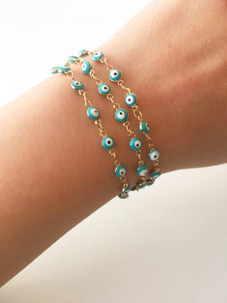 A minimalist evil eye bracelet featuring a gold link chain and turquoise glass beads, symbolizing protection and style.