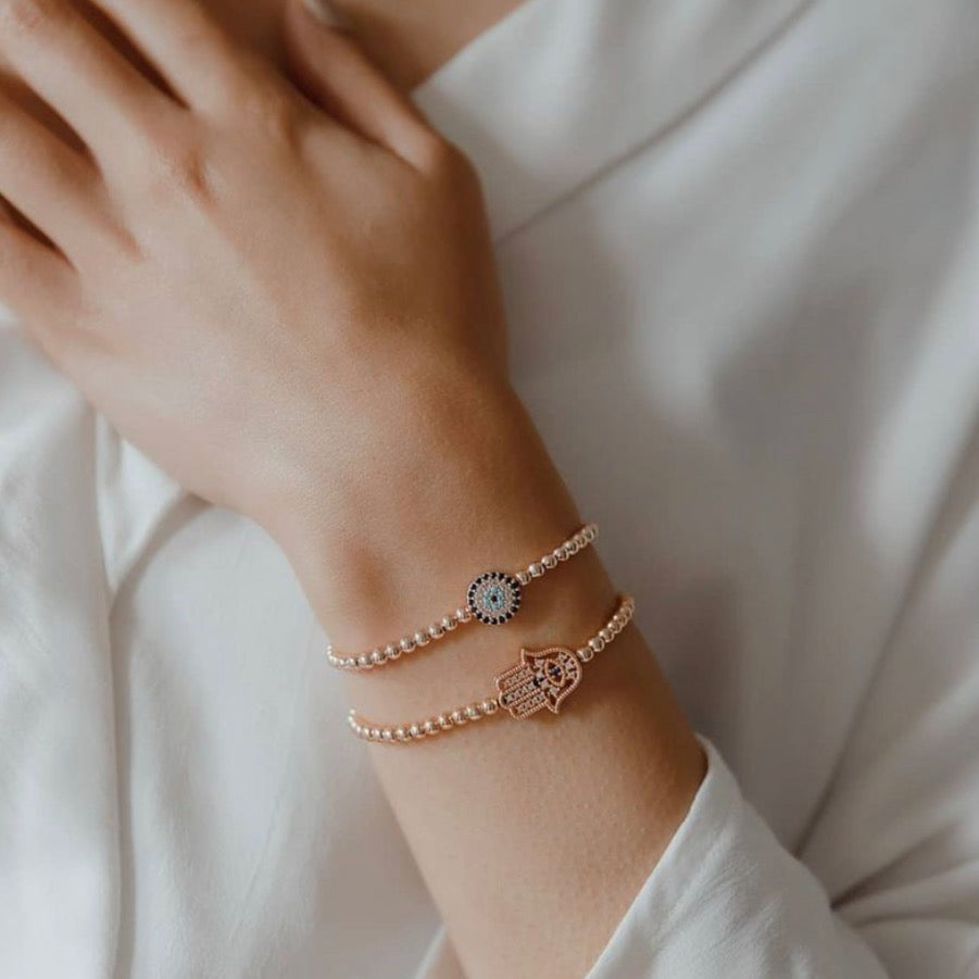 Adjustable Evil Eye and Hamsa bracelet in rose gold, featuring intricate designs and a beaded finish, perfect for stylish protection.