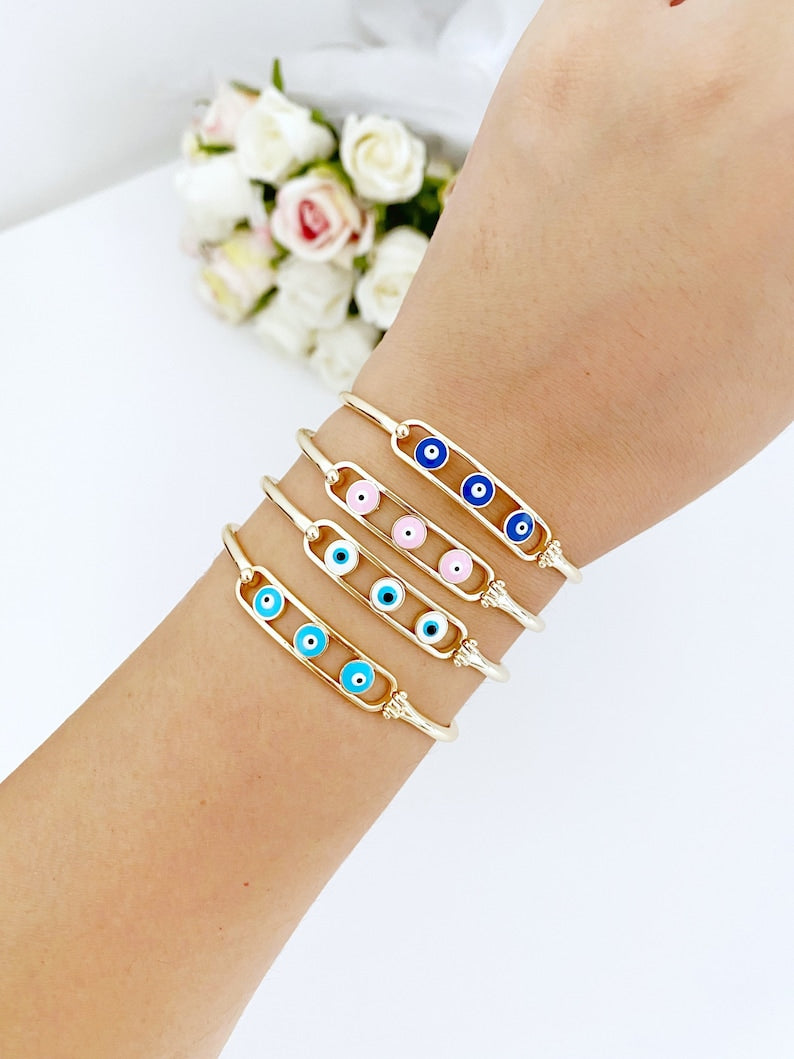 Elegant gold cuff Evil Eye Bracelet featuring a movable oval charm, available in four colors.