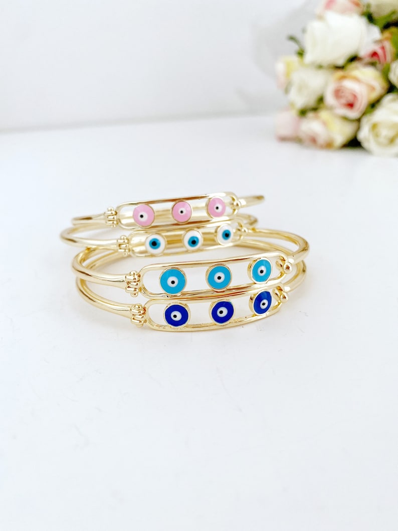 Elegant gold cuff Evil Eye Bracelet featuring a movable oval charm, available in four colors.