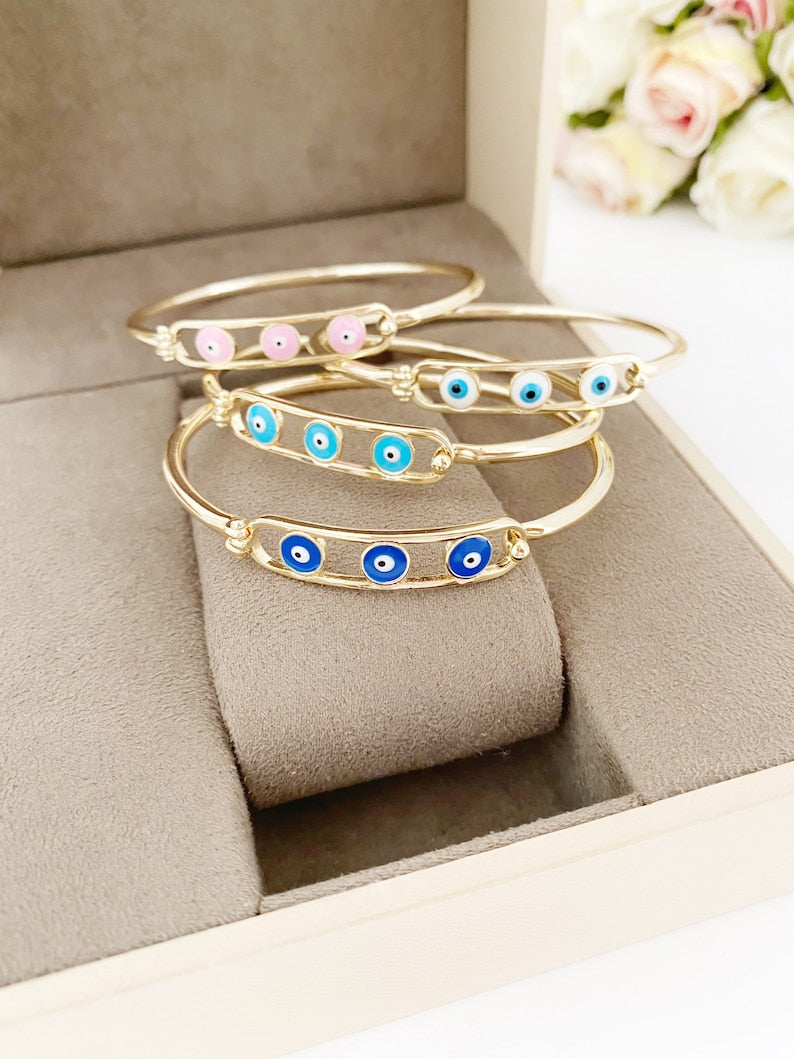 Elegant gold cuff Evil Eye Bracelet featuring a movable oval charm, available in four colors.