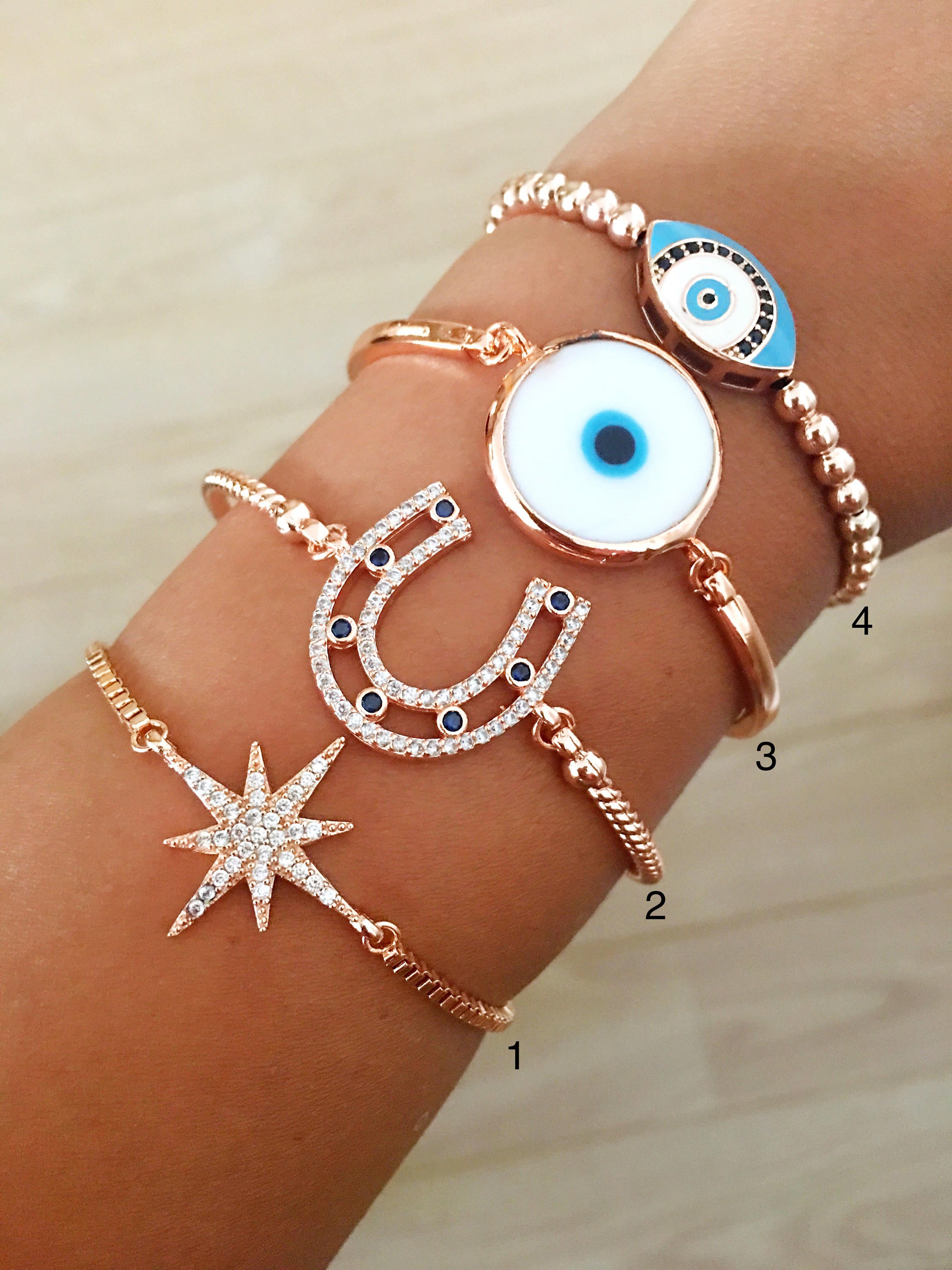 A collection of four unique Evil Eye Bracelets featuring star, horseshoe, Murano glass, and oval beaded designs, showcasing their elegant craftsmanship.