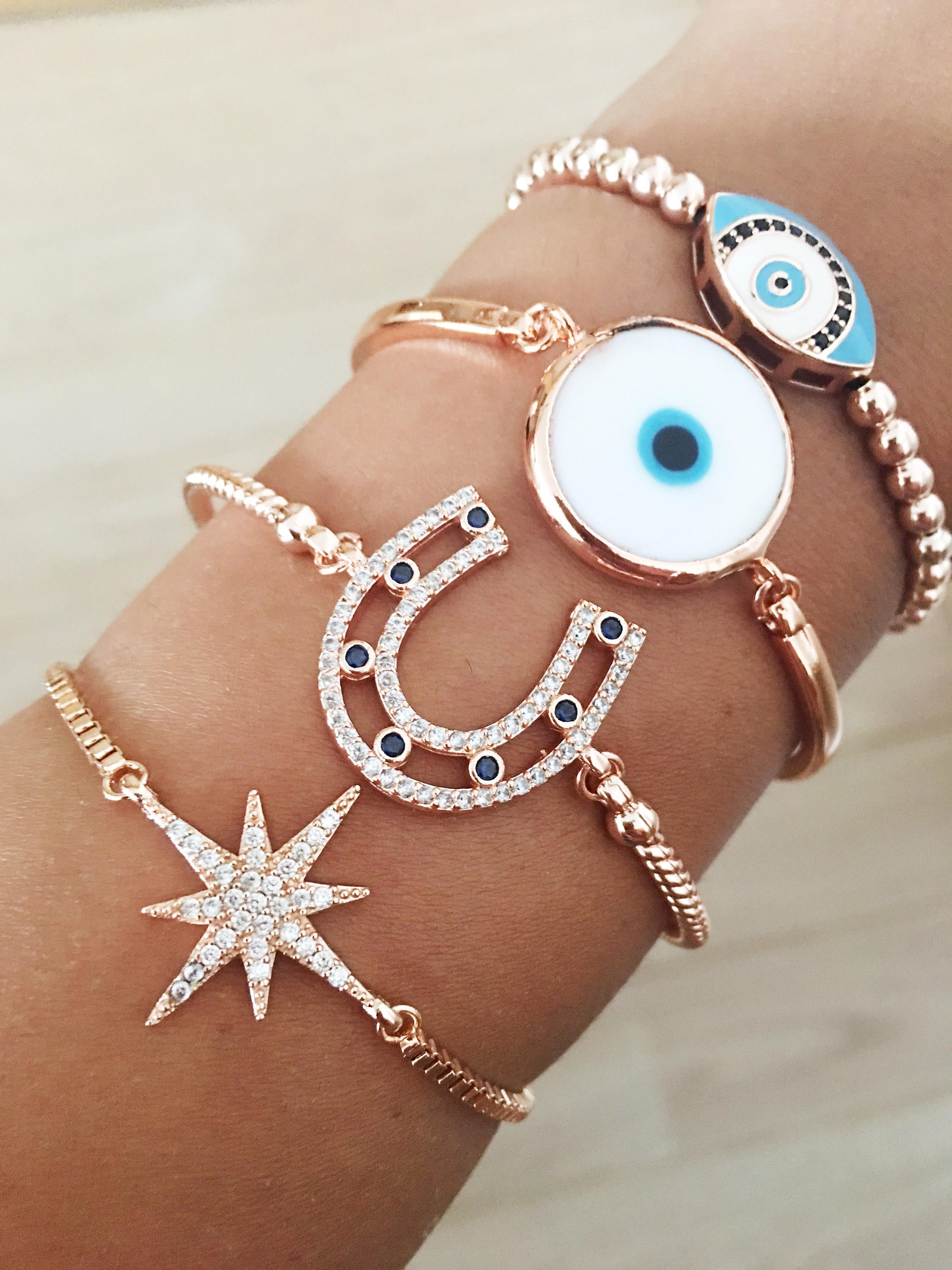 A collection of four unique Evil Eye Bracelets featuring star, horseshoe, Murano glass, and oval beaded designs, showcasing their elegant craftsmanship.